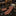 A patterned necktie and matching pocket square displayed on a black marble counter in a luxury dressing room setting. The tie and pocket square feature a rust-orange and dark brown chevron pattern.