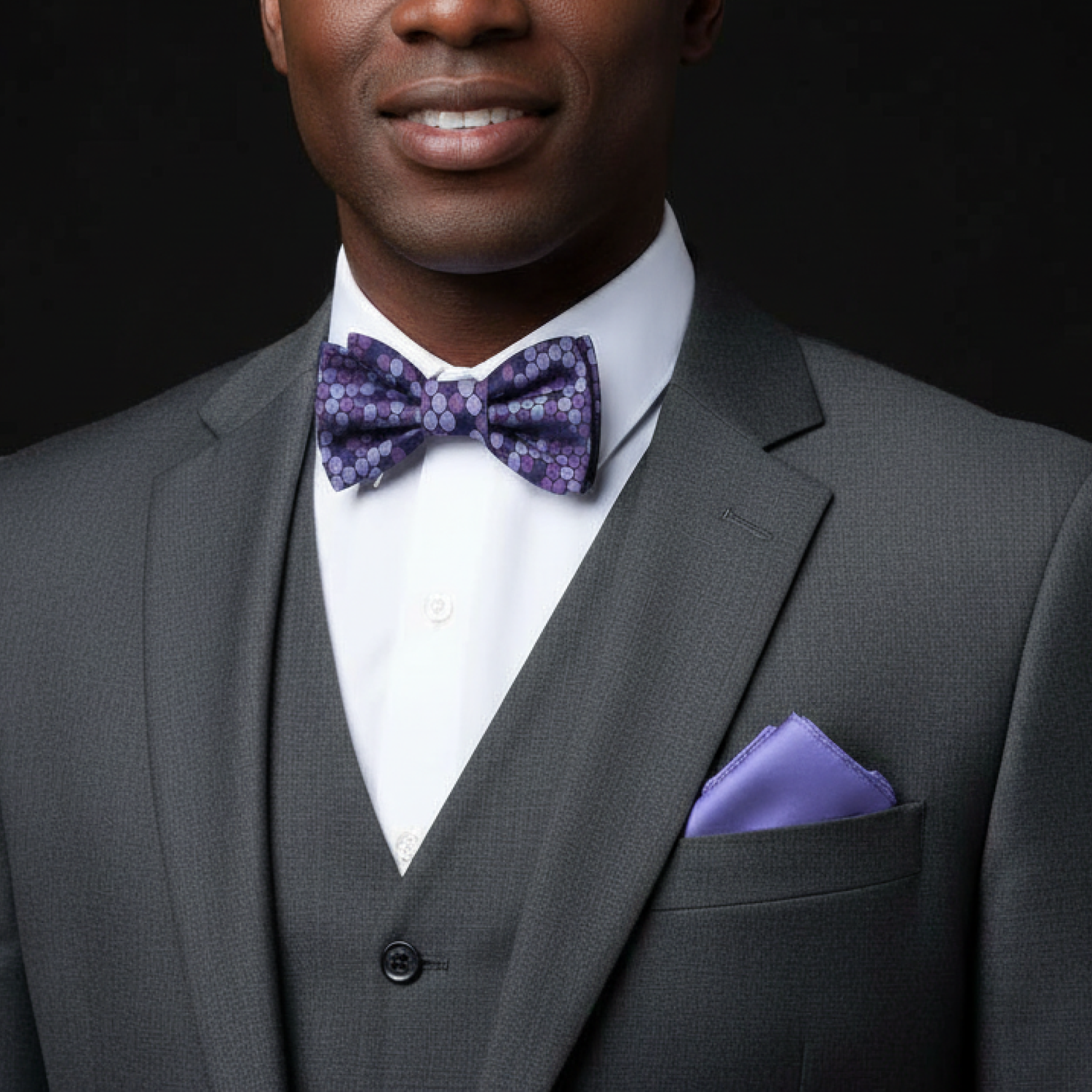 Man wearing a shades of purple polka dot bow tie and accenting light purple square