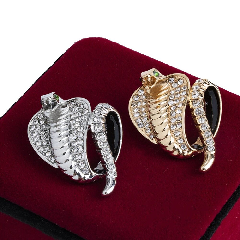 A Gold Colored and Silver Colored Cobra With Stones Lapel Pin On Top Of Burgundy Box
