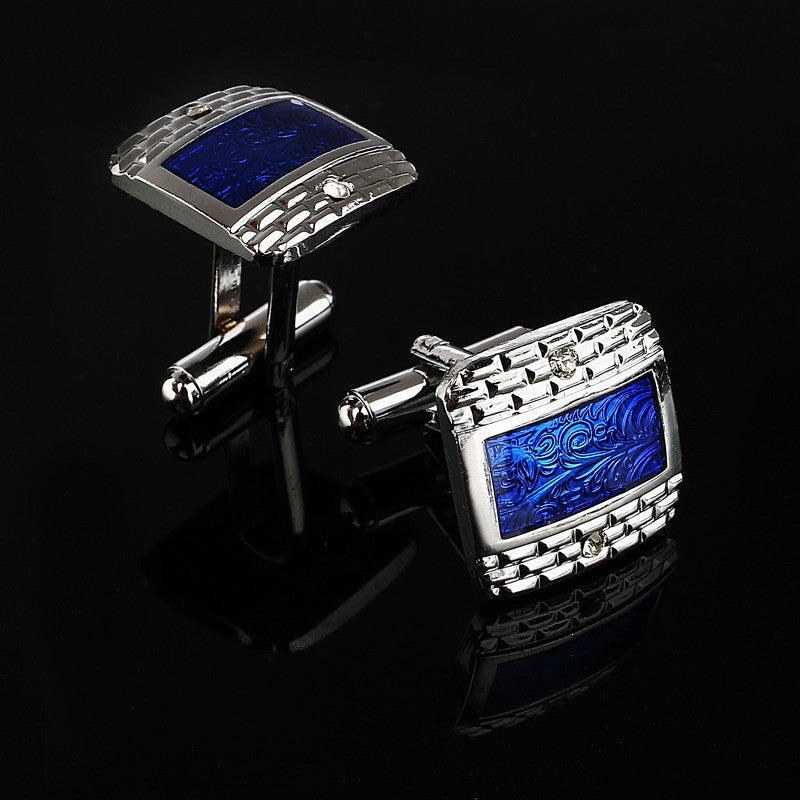 A chrome and blue colored rectangle shaped with checkerboard and waves detail pair of cuff-links