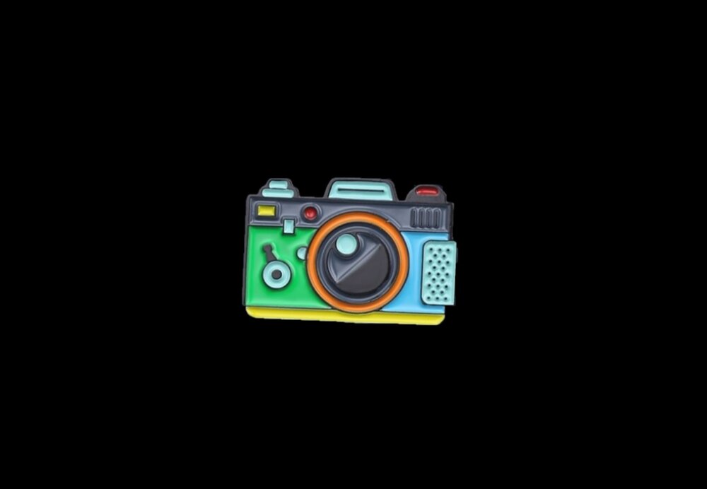 A Green, Blue, Yellow Colored Camera Shaped Lapel Pin.||Green, Blue, Yellow