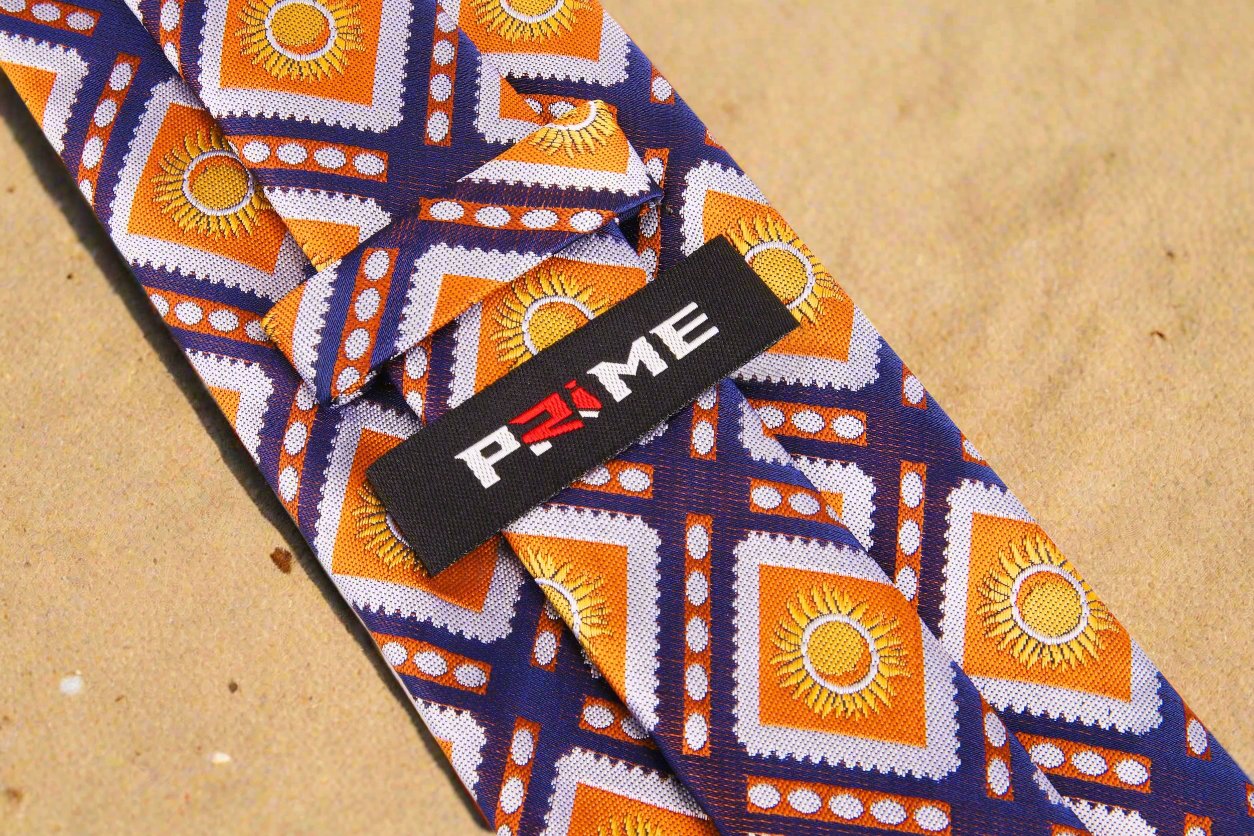 Logo View: A Dark Blue, Orange Sunburst Design Silk Zipper Necktie With Logo On Back Of Tie Keep Loop