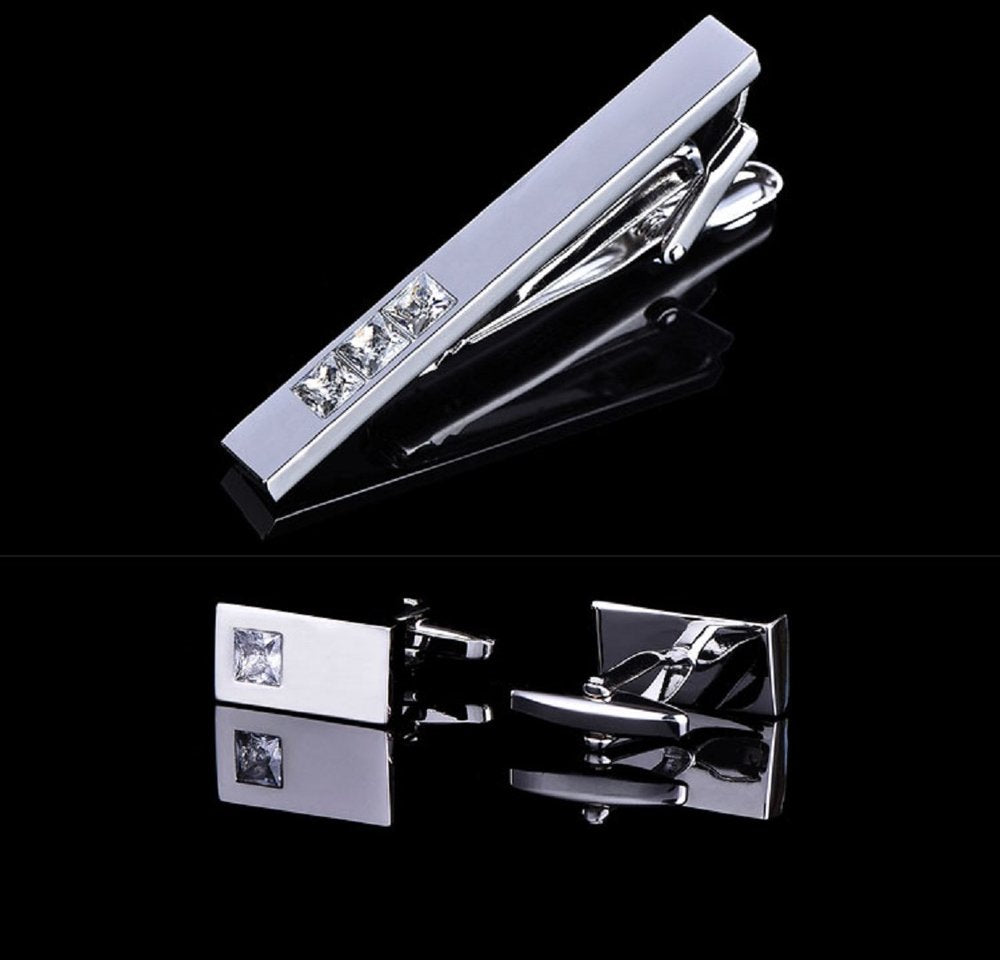 A chrome colored tie bar and cuff-links with clear stones